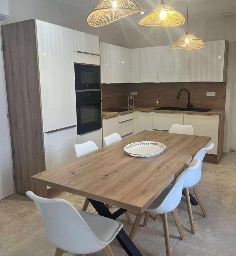 Modern kitchen equipped with Le Chant des Mésanges gîte with large wooden table and hanging luminaires.