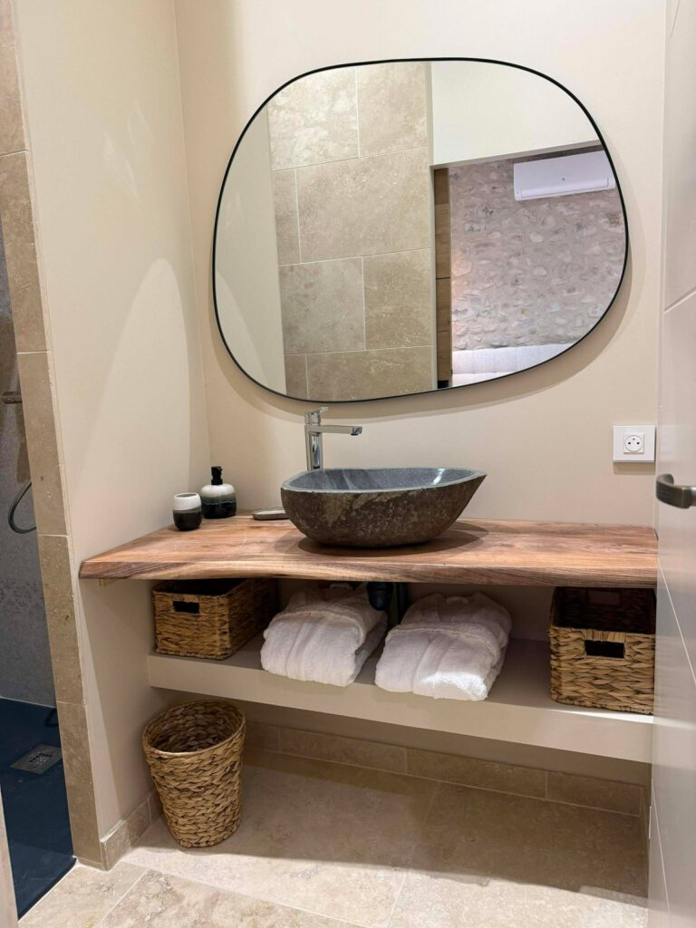 Private bathroom with stone basin and wooden furniture at the Bulle des Mésanges in the Drôme